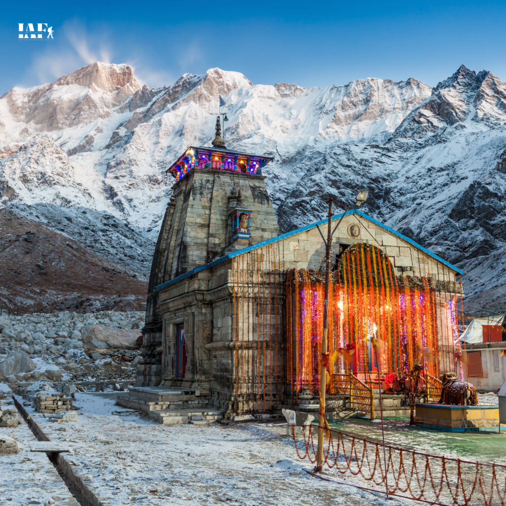 Front view of Kedarnath Temple with decorated entrance and snow-covered Himalayan mountains behind.