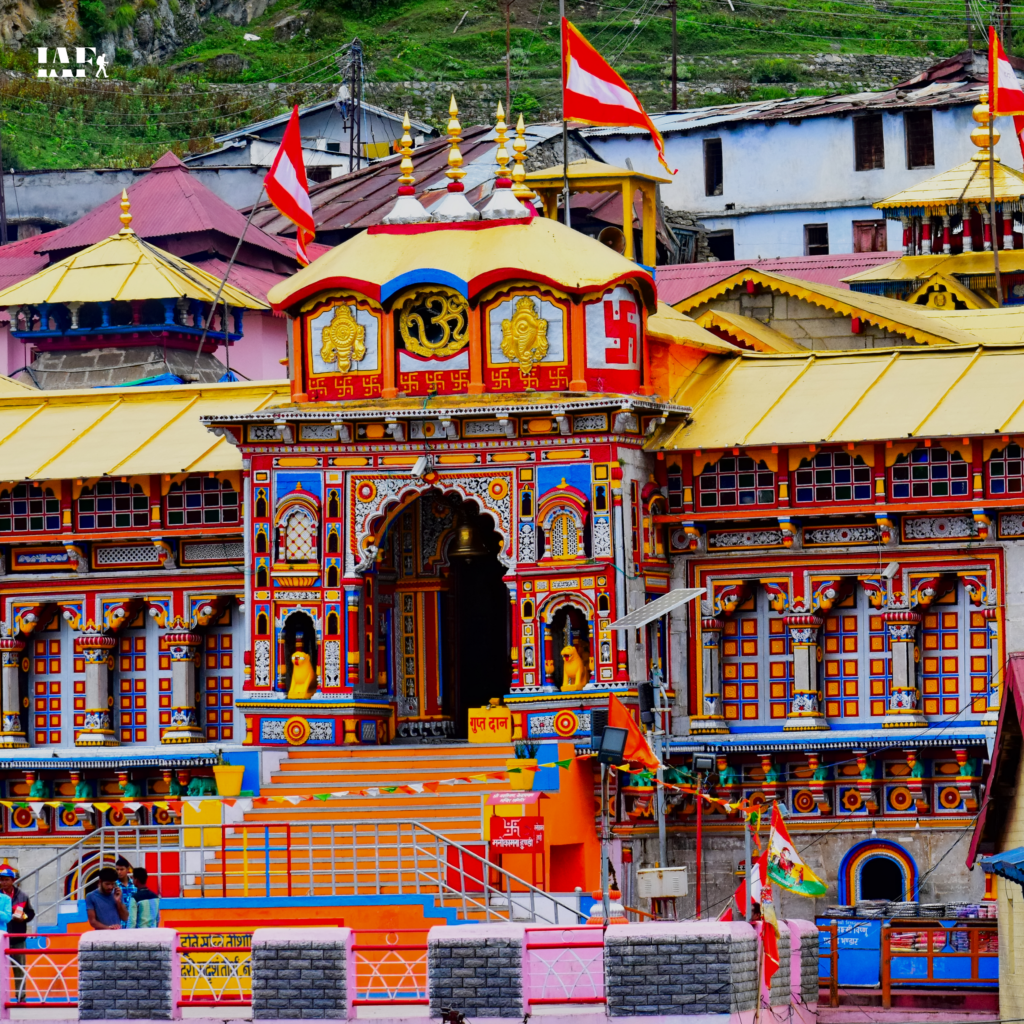 Colorful Badrinath Temple facade with golden roof and red flags in Uttarakhand.