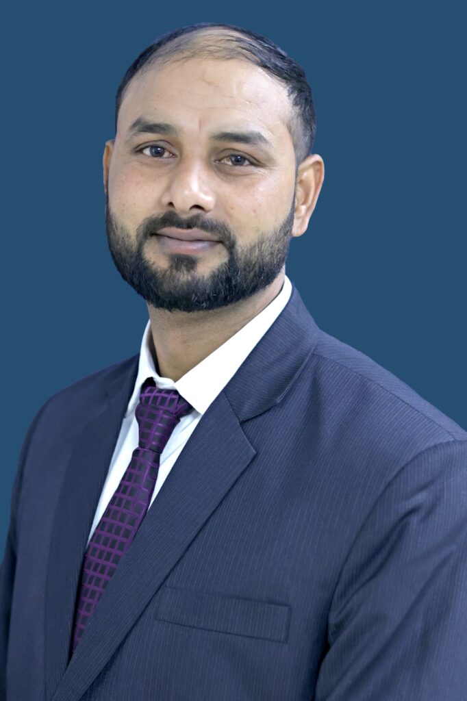Portrait of Jitendra Puri (Tony), Co-Founder of Indian Adventure Fusion, wearing a dark suit and purple tie against a blue background.